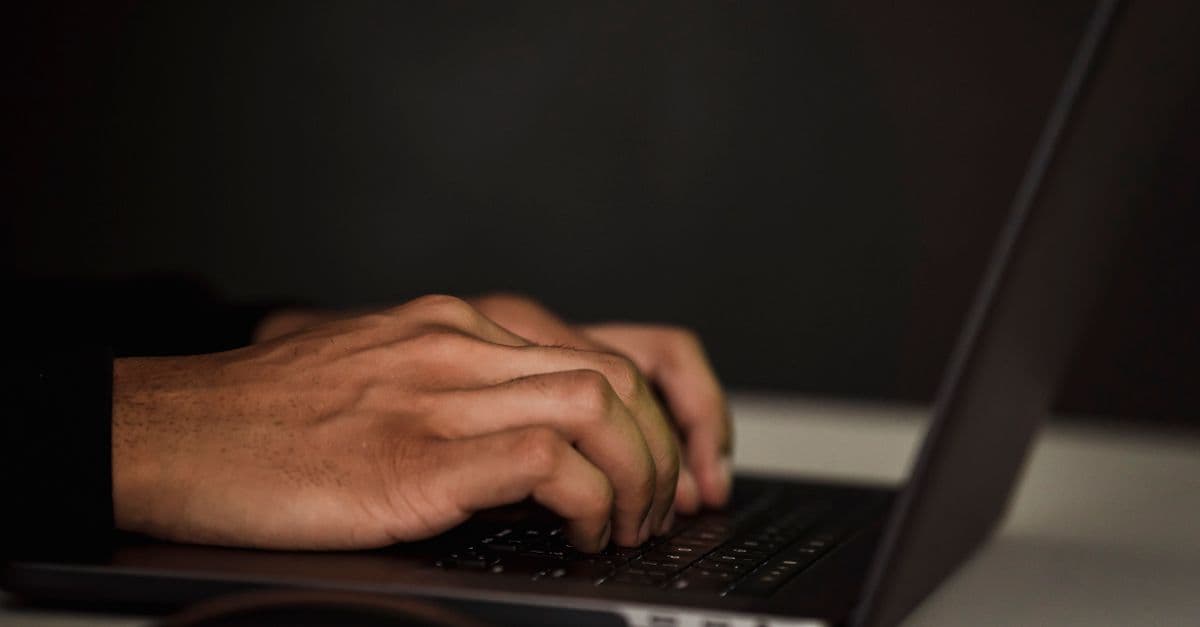 Hands typing a prompt on a laptop keyboard at a desk.